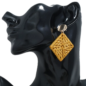 Gros plan d'une boucle d'oreille tressée géométrique jaune sur mannequin noir