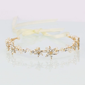 Detail of golden bridal headband with sparkling crystals, pearls and ribbon ties