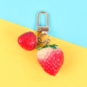 Cute strawberry keychain with red and pink fruit charms on vibrant two-tone background