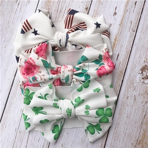 Three infant headbands with American flag, rose, and clover patterns on white wood