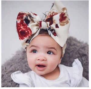 Close-up of a floral baby headband with a large bow on a cute infant model