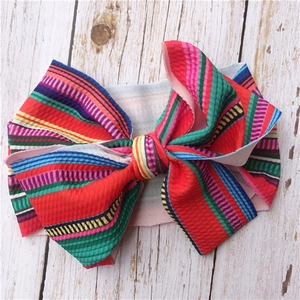 Detail of colorful striped waffle knit headband with a large bow for infants and toddlers
