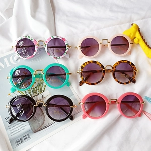 Flat lay of colorful round frame kids sunglasses with UV 400 protection on white fabric