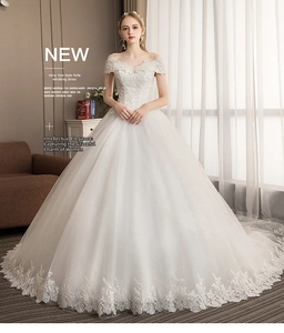 Detail of elegant off-shoulder white bridal gown featuring intricate lace and long train