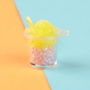 Macro shot of miniature luminous smoothie cup with yellow crushed ice and pink beads inside