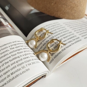 Elegant gold-plated silver earrings with round white pearls on minimalist English magazine