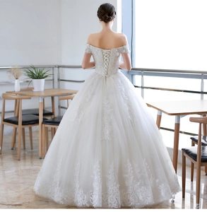 Detail of white off-shoulder bridal gown with lace embroidery and lace-up back closure