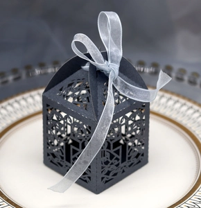 Detail of laser-cut grey favor box with silver bow ribbon on white decorative plate