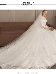 Detail of elegant white wedding dress featuring intricate lace embroidery and long train
