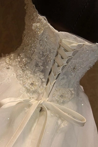 Detailed close-up of intricate lace embroidery and beaded lace-up back of white bridal gown