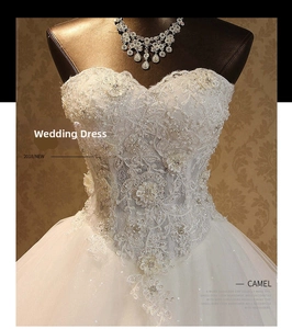 Detailed view of intricate lace flower patterns and beadwork on a white bridal gown