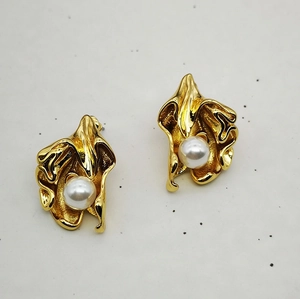 Detail view of white pearl set in pleated 18K gold plated brass irregular flower stud earring