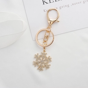 Elegant gold snowflake keychain with sparkling rhinestones on a white gift background