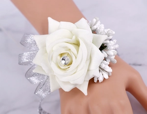 Detail of white bridal wrist corsage with faux rose, crystal center and silver ribbon