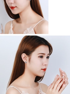 Close-up of minimalist silver flower earrings with crystals worn by a model in soft lighting