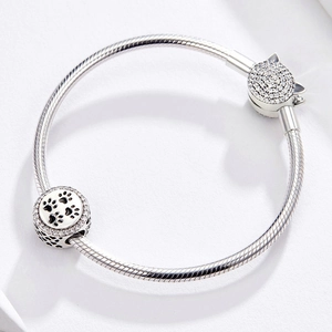 Detailed macro of a silver snake chain bracelet featuring a cat paw print charm with zircons