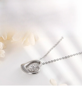 Detailed macro shot of silver heart pendant with a sparkling crystal-encrusted sphere center