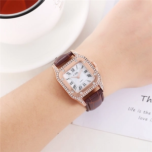 Close-up of women's square rose gold quartz watch with rhinestones on brown leather strap