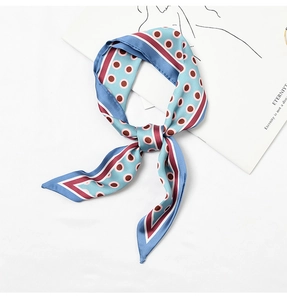 Close-up of a blue silk scarf with burgundy polka dots tied into a stylish bow
