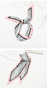 Detail of a pink and black striped silk scarf tied in a bow on a white background