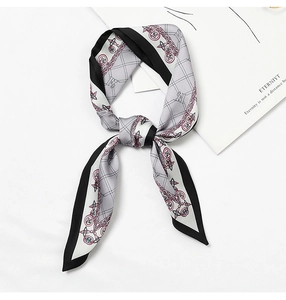 Detail of grey silk scarf with black borders tied in a bow featuring a chain pattern