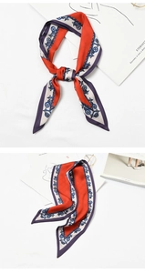 Detailed view of the orange silk scarf with blue chain patterns and knotted styling