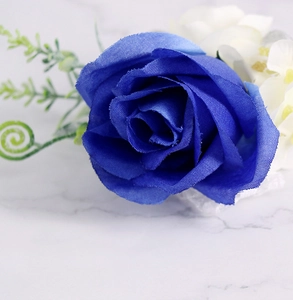 Detailopname van koningsblauwe zijden roos corsage met groene bladeren voor bruiloft