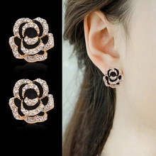 Detail view of crystal camellia flower earrings with silver finish on a model's ear