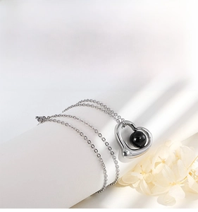 Detail of a heart-shaped projection necklace with a black stone on a minimalist chain