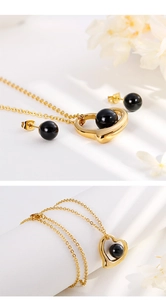 Detailed view of heart-shaped gold necklace and earrings set with black beads