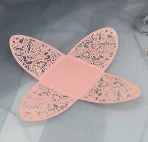 Flat lay of laser-cut pink paper wedding candy box with intricate floral hollow design