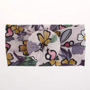 Primer plano de una diadema de nailon suave para bebé con estampado floral y nudo