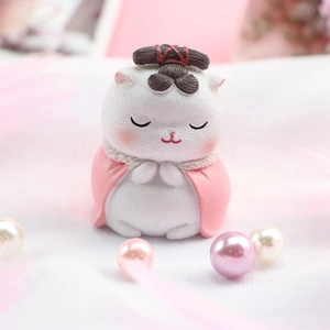 Detail einer weißen Katzenfigur im rosa Umhang mit Haarknoten für Tortendeko