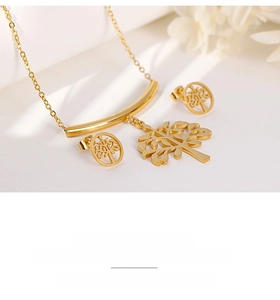 Macro detail of gold tree of life necklace and earrings set on white textured card