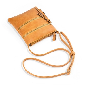 Detailed view of yellow crossbody bag featuring triple gold zippers and a leather tassel