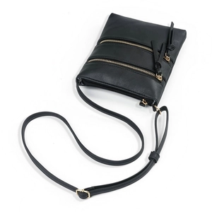 Detail view of black faux leather crossbody bag with multiple gold zippers and compartments