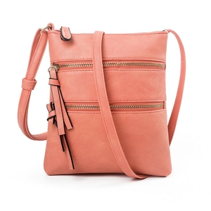 Detail view of pink leather crossbody bag with dual metal zippers and long tassel charm