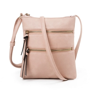 Detail of soft pink pebble leather crossbody bag featuring dual zippers and tassel pulls