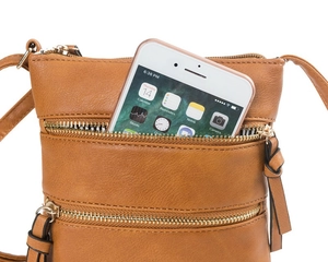 Detail of brown litchi leather crossbody bag with dual zipper pockets holding a smartphone