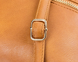 Detailed macro view of brown leather texture with premium gold metal buckle and zipper