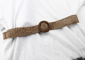 Détail macro de ceinture tressée marron avec boucle ronde en bois sur robe blanche