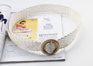 Vue détaillée d'une ceinture tressée blanche avec boucle ronde en bois sur un magazine