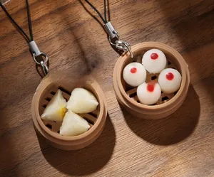 Close-up of realistic dim sum buns and shrimp dumplings keychain on a wooden table
