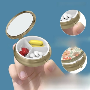 Detail of golden pill box with three compartments, mirror and vintage floral pattern cover