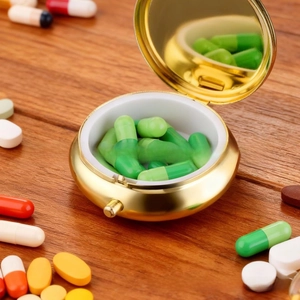 Detail of round golden metal pill box with built-in mirror and three internal compartments
