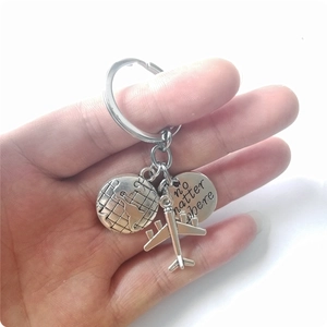 Detail of metal travel keychain with airplane, globe charms and engraved tag