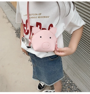 Pink pig-shaped mini shoulder bag for kids in leather material shown in outdoor setting