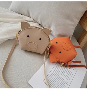 Detail of cute pig-shaped PU leather mini crossbody bags in beige and orange colors