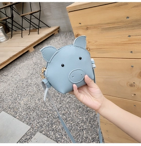 Detailed view of mini blue cartoon pig shoulder bag made of PU leather with long strap