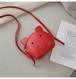 Detail of red cartoon pig shoulder bag made of PU leather with thin strap on beige background